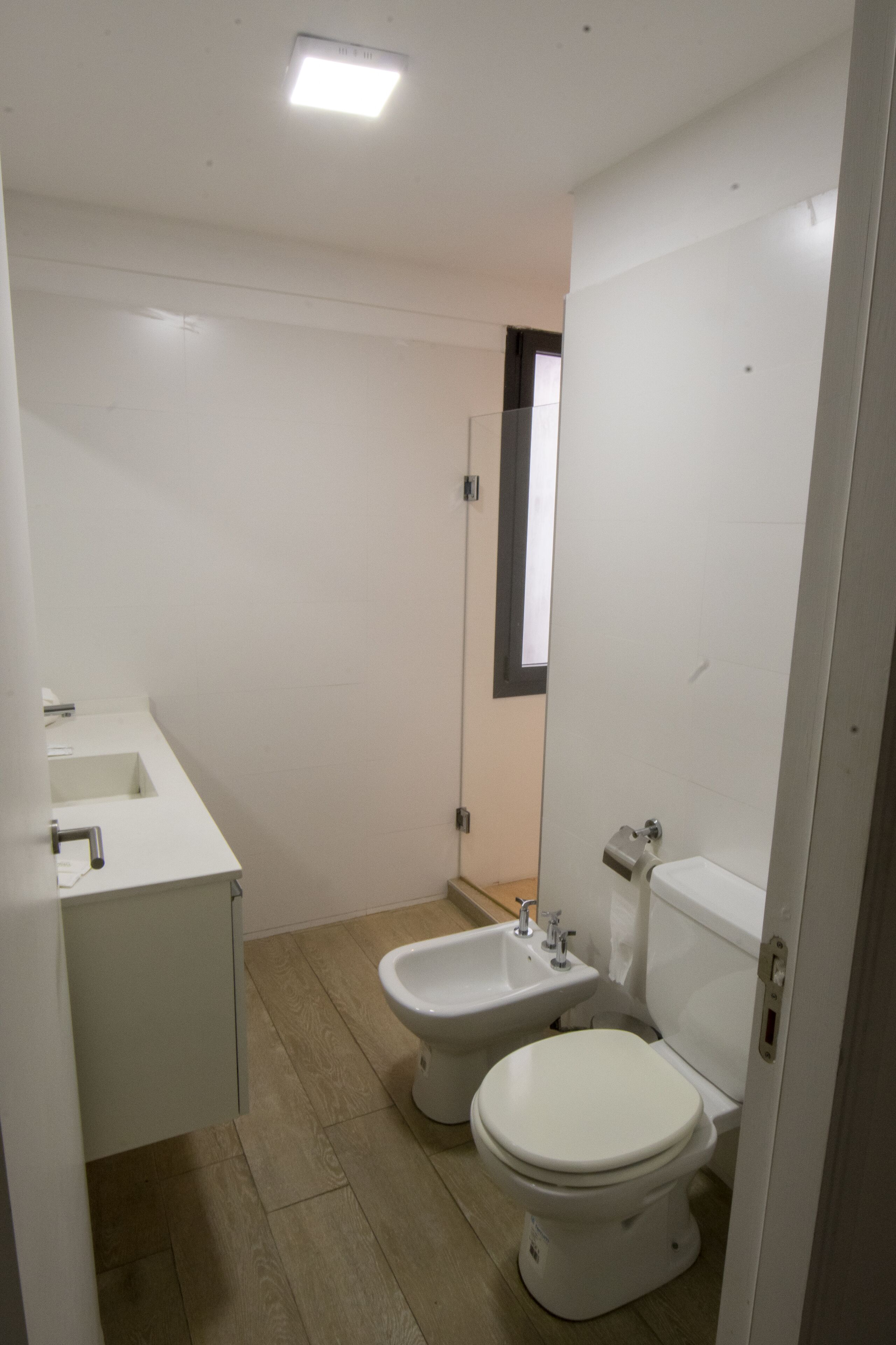 A small, modern bathroom with a toilet, bidet, and sink.