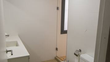 A small, modern bathroom with a toilet, bidet, and sink.
