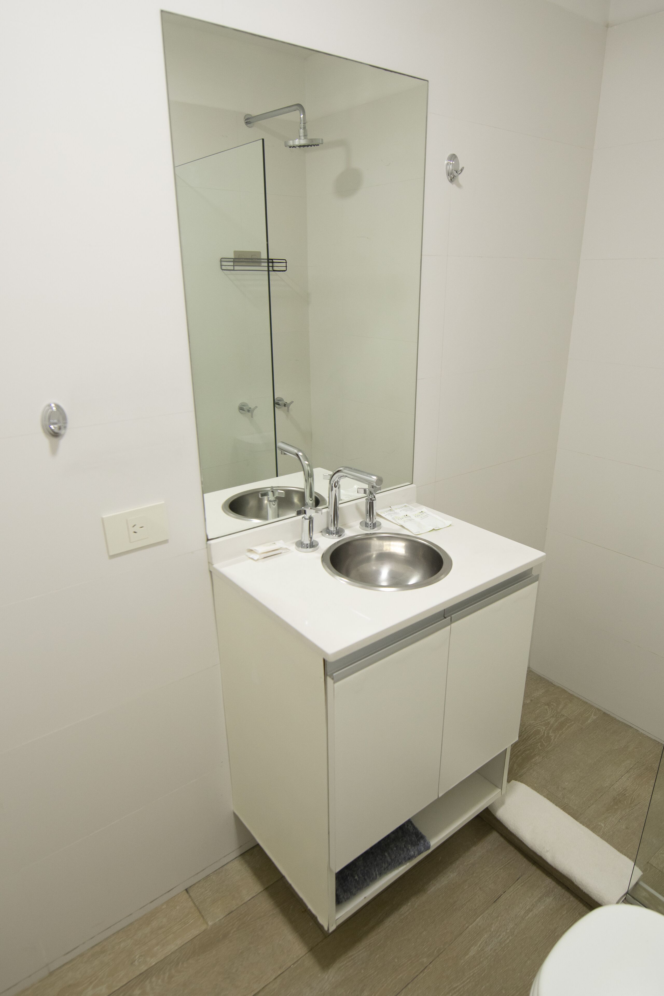 A modern bathroom with a glass-enclosed shower, a double sink, and a large mirror.