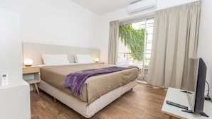 A hotel room with a bed, bedside table, TV, and a balcony with curtains. - Babel Belgrano (Buenos Aires)