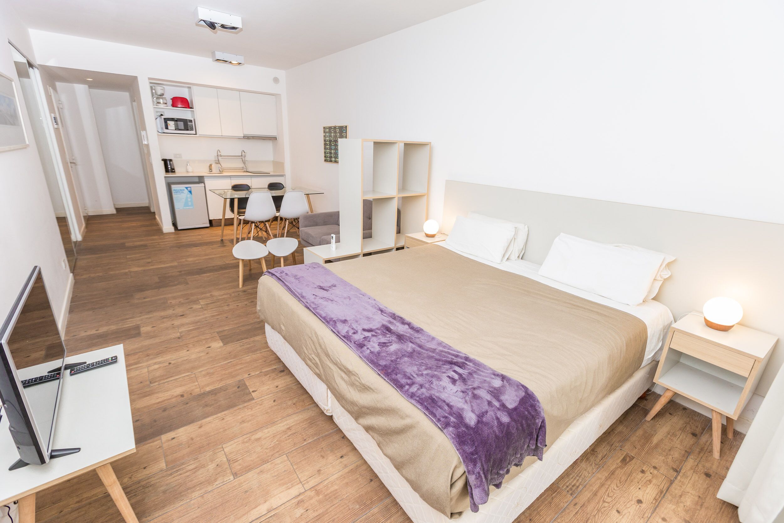 Una moderna camera d'albergo con un letto grande, una scrivania con computer, un angolo cottura e una zona pranzo separata.