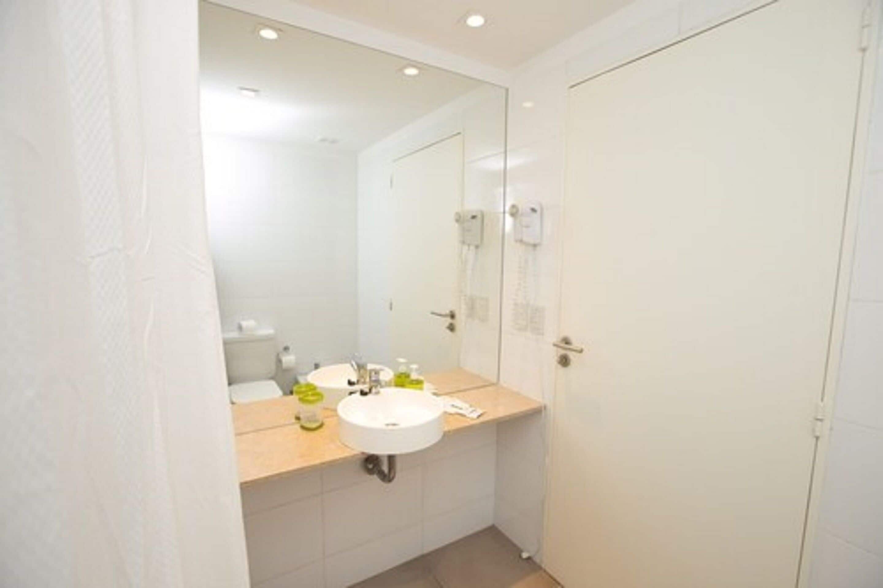 A bathroom with a white sink, mirror, and a white door.