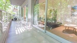 A balcony with a glass door, white chairs, and a small round table. - Babel Belgrano (Buenos Aires)