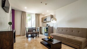 Un salon moderne comprenant un canapé, une table basse, un téléviseur et un coin repas avec des chaises et une table.