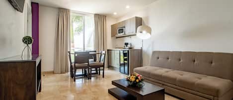 Een moderne woonkamer met een bank, salontafel, televisie en een eethoek met stoelen en een tafel.