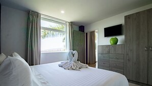 Une chambre d’hôtel avec un grand lit, une armoire, un téléviseur à écran plat et une fenêtre avec des rideaux.