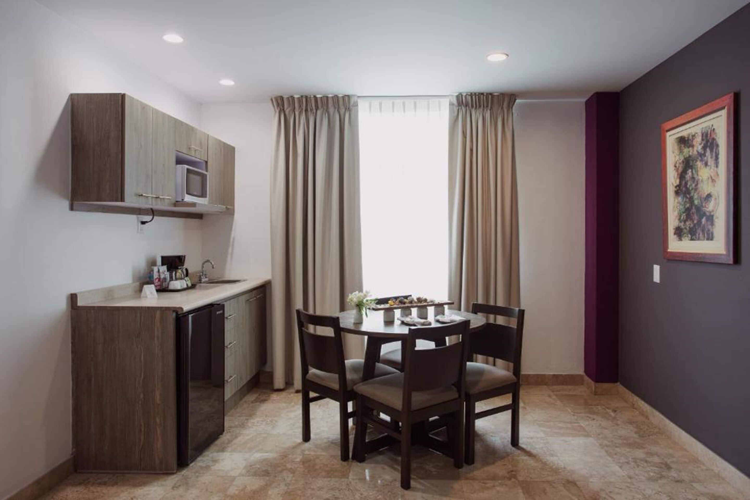 A compact kitchen with a microwave, a small sink, and a dining table with four chairs.
