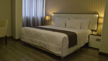 Een hotelkamer met een groot bed, een nachtkastje met een lamp en een stoel.