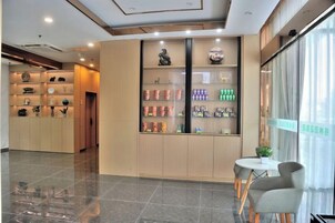 Vestíbulo de hotel con mostrador de recepción, área de estar y exhibición de productos.