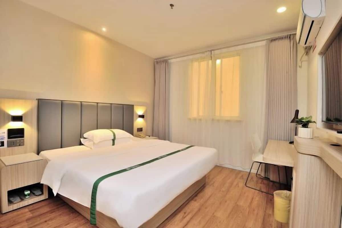A hotel room with a bed, bedside lamps, a desk, and a window with curtains.