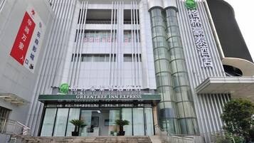 Um edifício moderno com uma placa de destaque para 'GREENTREE INN EXPRESS' na entrada.