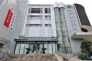Un edificio moderno con un letrero llamativo para 'GREENTREE INN EXPRESS' en la entrada.
