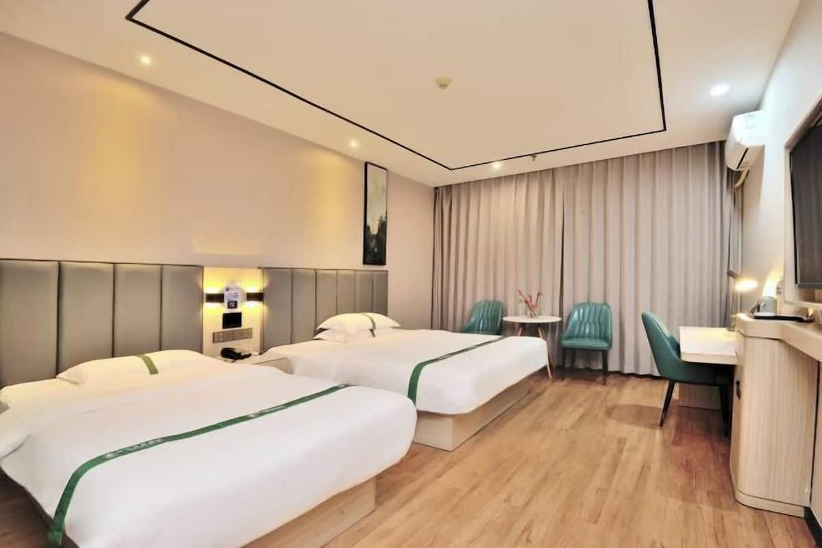 A hotel room with two beds, a desk, chairs, a small table, and a large window with curtains.