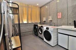 A modern laundry room with a washing machine, dryer, and ironing station. - GreenTreen Alliance Hotel Suzhou Mudu Town Jinshan Road Branch (Suzhou)