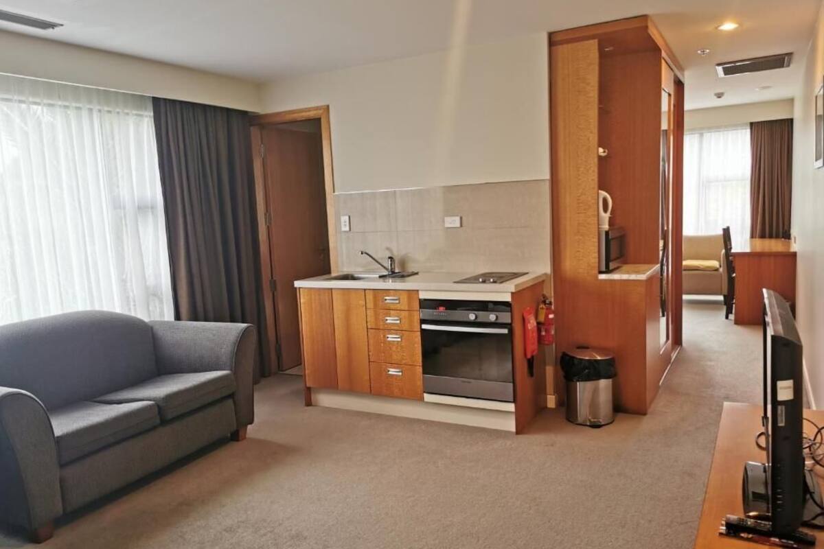 A compact living space with a kitchenette, a sofa, and a television.