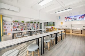 Una biblioteca moderna con estanterías, mesas y taburetes.