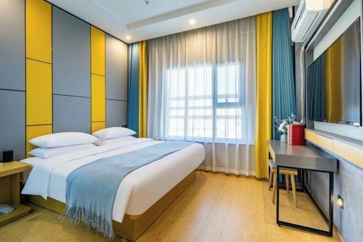 Une chambre d’hôtel moderne avec un grand lit, un bureau et une fenêtre avec des rideaux.