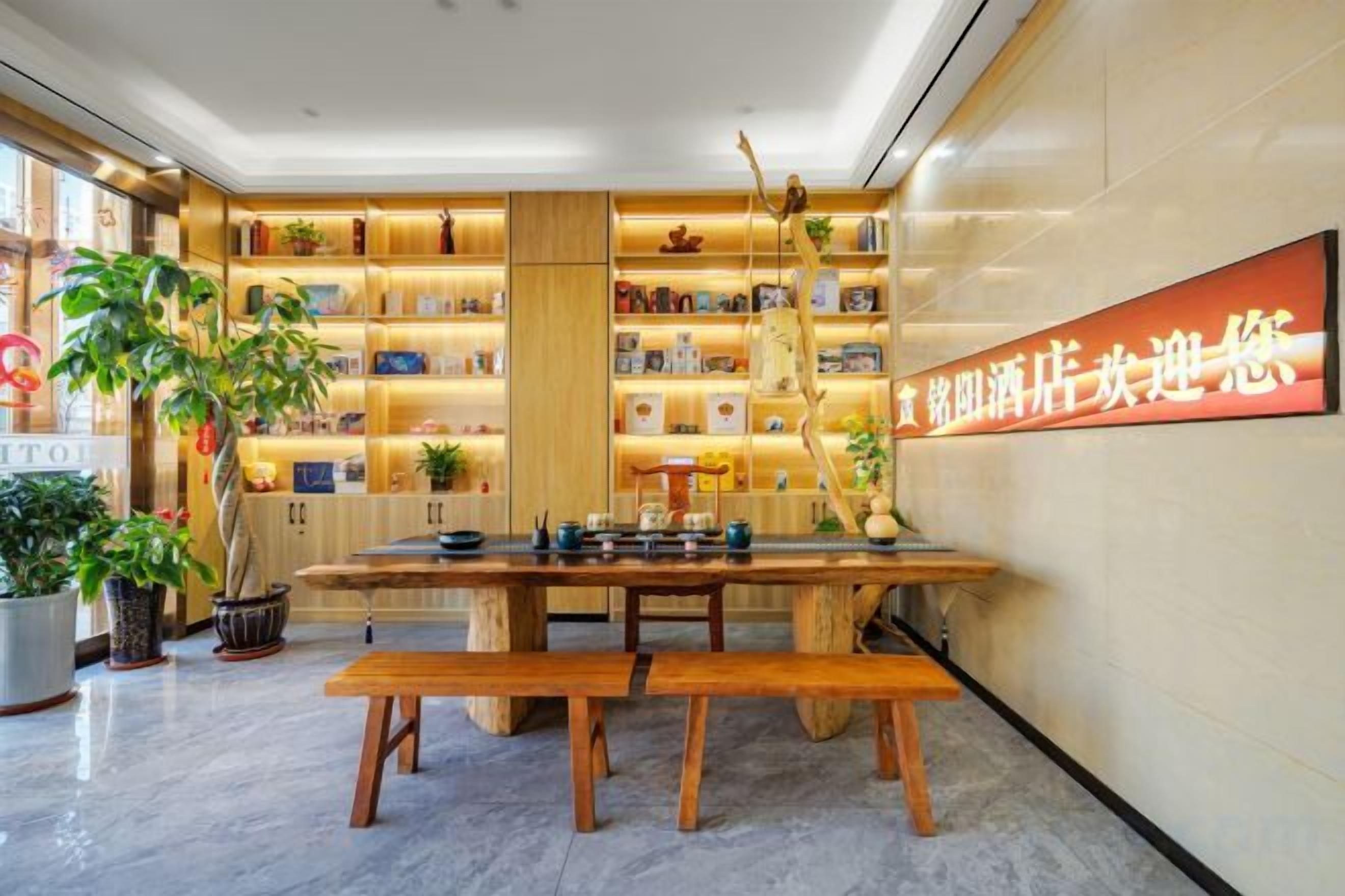 A modern interior with a wooden table and benches, surrounded by shelves with various items and a large illuminated sign.
