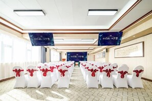 A conference room with rows of white chairs tied with red ribbons, a large screen at the front, and banners on the walls. - OTA short name: Mingyang Hotel (Taiyuan South Railway Station · Shanxi University Branch) (Taiyuan)