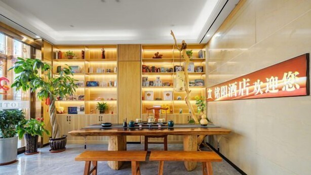 A hotel lobby with a wooden reception desk, shelves with books and decorative items, and a large sign with Chinese characters. - OTA short name: Mingyang Hotel (Taiyuan South Railway Station · Shanxi University Branch) (Taiyuan)