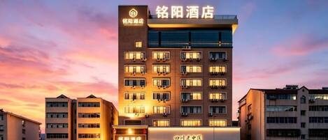 A hotel with multiple floors, a prominent sign, and a well-lit facade.