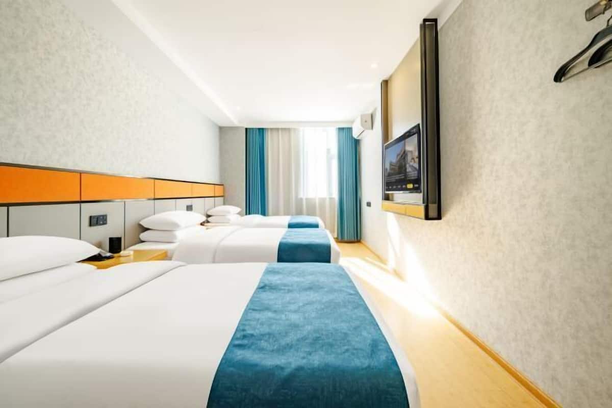 Une chambre d’hôtel avec deux lits, un bureau, une télévision et une fenêtre avec des rideaux.