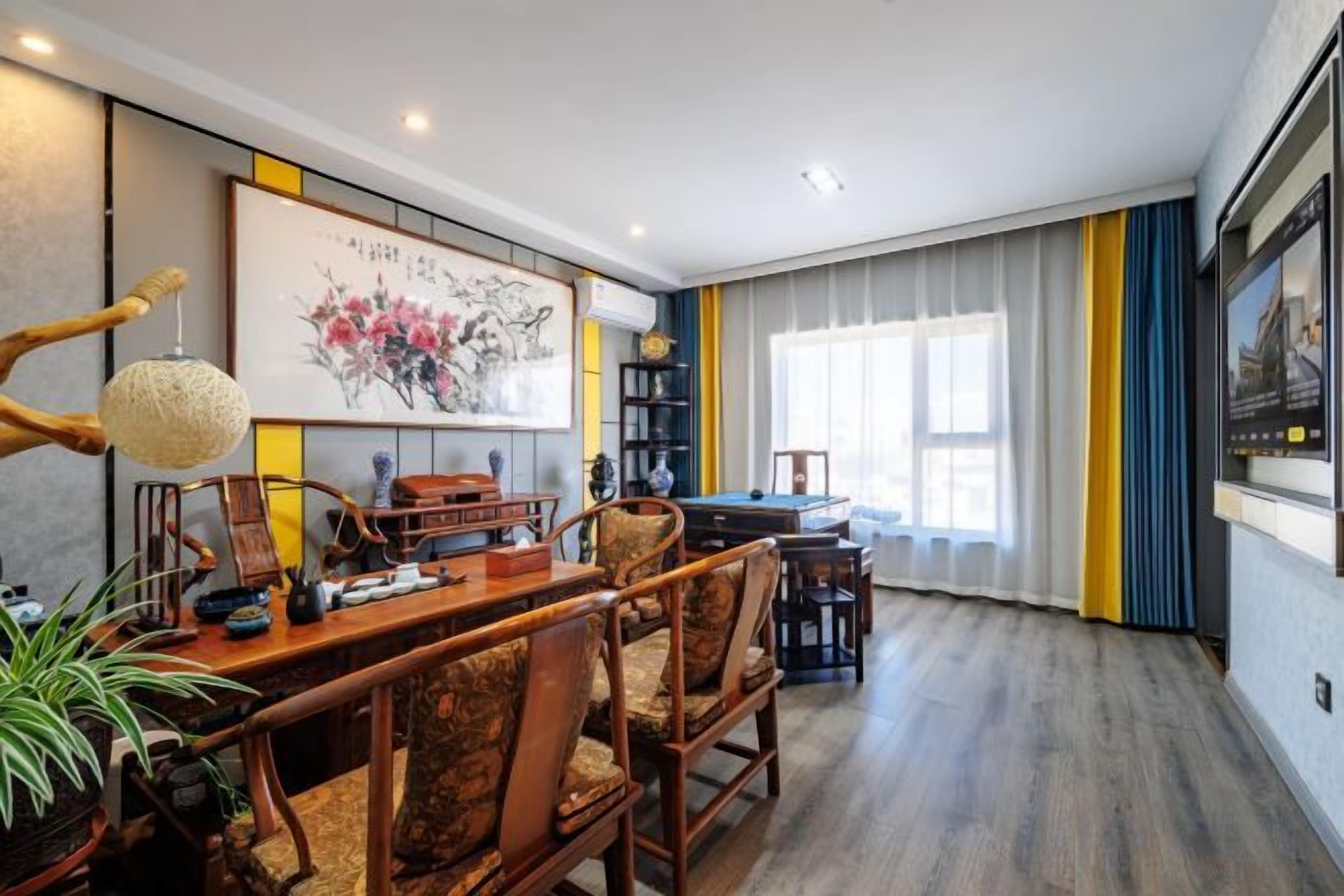 A dining area with a wooden table and chairs, a hanging light fixture, and a painting on the wall.