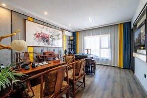 Un área de comedor con una mesa y sillas de madera, una lámpara colgante y un cuadro en la pared.