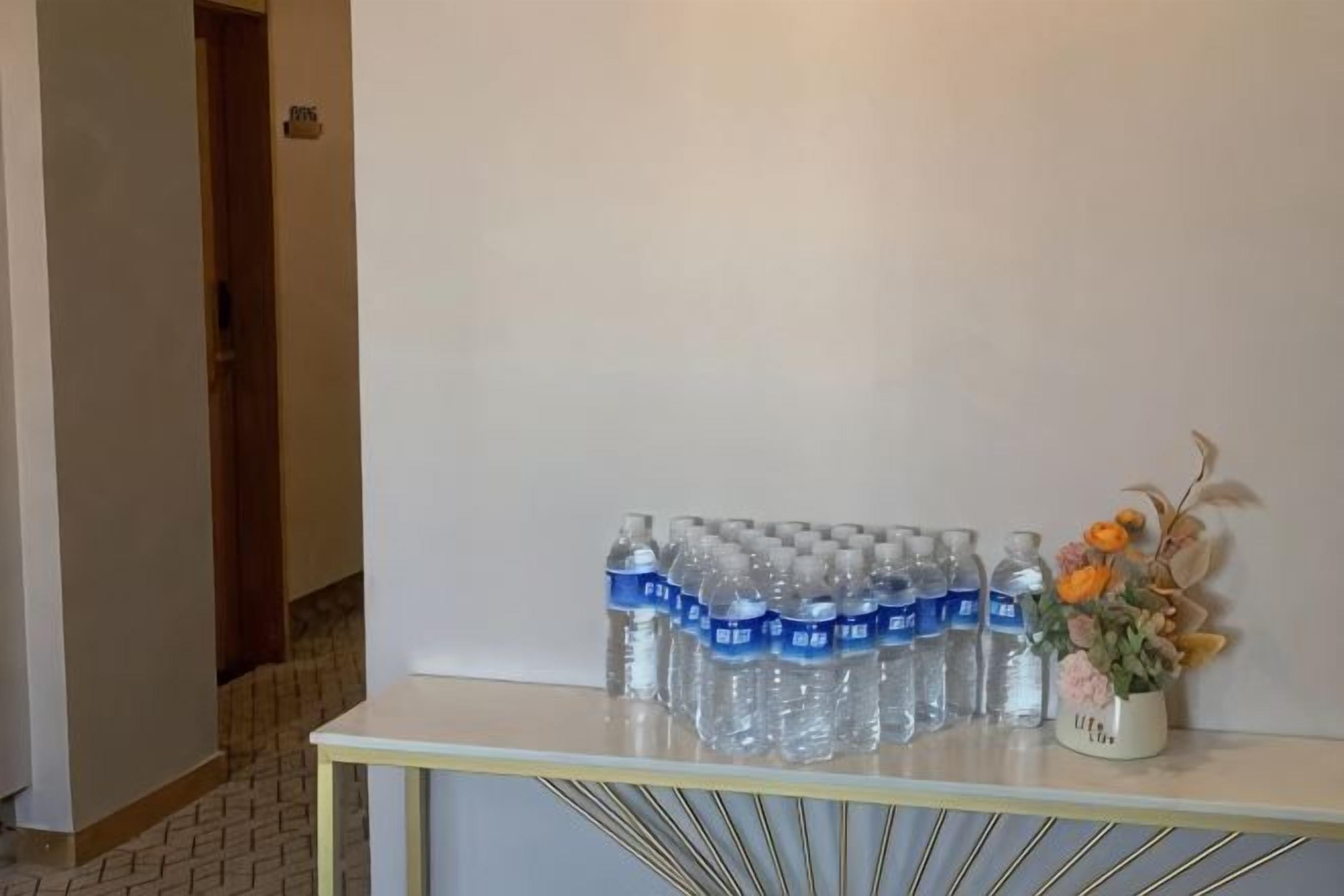 A reception area with a white console table displaying water bottles and a small potted plant.