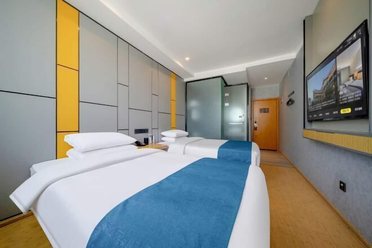Une chambre d’hôtel avec un grand lit, un téléviseur fixé au mur et un plancher en bois.