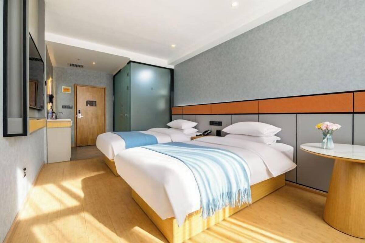 Une chambre d’hôtel moderne avec un grand lit, une table de chevet et une petite table ronde agrémentée d’un vase de fleurs.