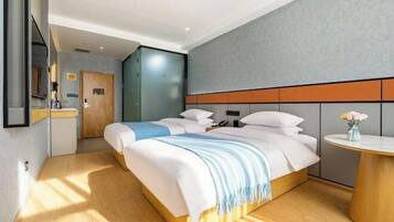Una habitación de hotel moderna con una cama grande, una mesita de noche y una pequeña mesa redonda con un jarrón de flores.