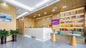 A modern reception area with a wooden reception desk, a flat-screen TV, and a bookshelf with various items. - OTA short name: Mingyang Hotel (Taiyuan South Railway Station · Shanxi University Branch) (Taiyuan)