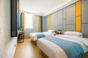 Habitación de hotel con dos camas, un escritorio y un ventanal grande con cortinas.