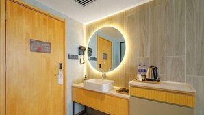 A hotel bathroom with a wooden door, a sink with a mirror, and a coffee machine. - OTA short name: Mingyang Hotel (Taiyuan South Railway Station · Shanxi University Branch) (Taiyuan)