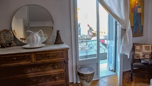 Ett rum med en byrå i trä, en vit kanna och en liten julgransprydnad. En stor spegel står på byrån, och det finns en dörr som leder ut.