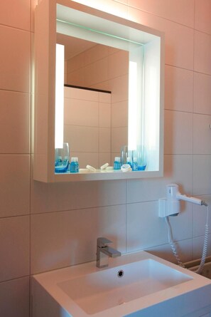 A bathroom with a white sink, a mirror, and a hairdryer.