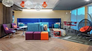 Ein stilvoller Lounge-Bereich mit blauem Sofa, bunten Stühlen, einem Hängesessel und einem kleinen Tisch.