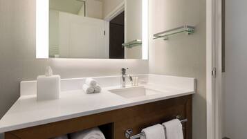 Une salle de bain moderne avec un lavabo blanc, un miroir et un porte-serviettes.