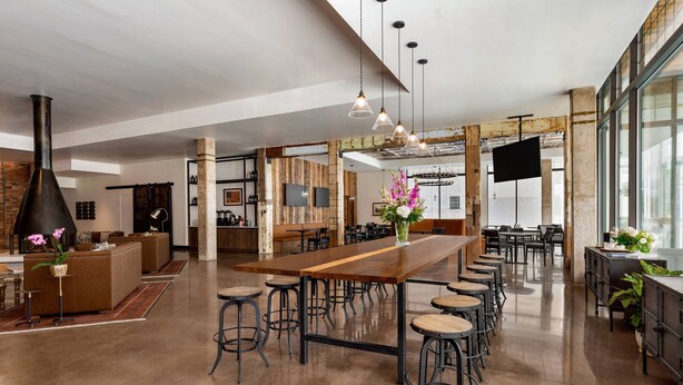 Une cuisine spacieuse et moderne, dotée d’un grand îlot central en bois, de tabourets de bar et d’un téléviseur de grande taille.