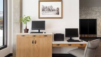 Un espacio de oficina moderno con un mueble de madera, dos monitores de computadora, un escritorio, una silla, una fotografía enmarcada en la pared y una planta en maceta.