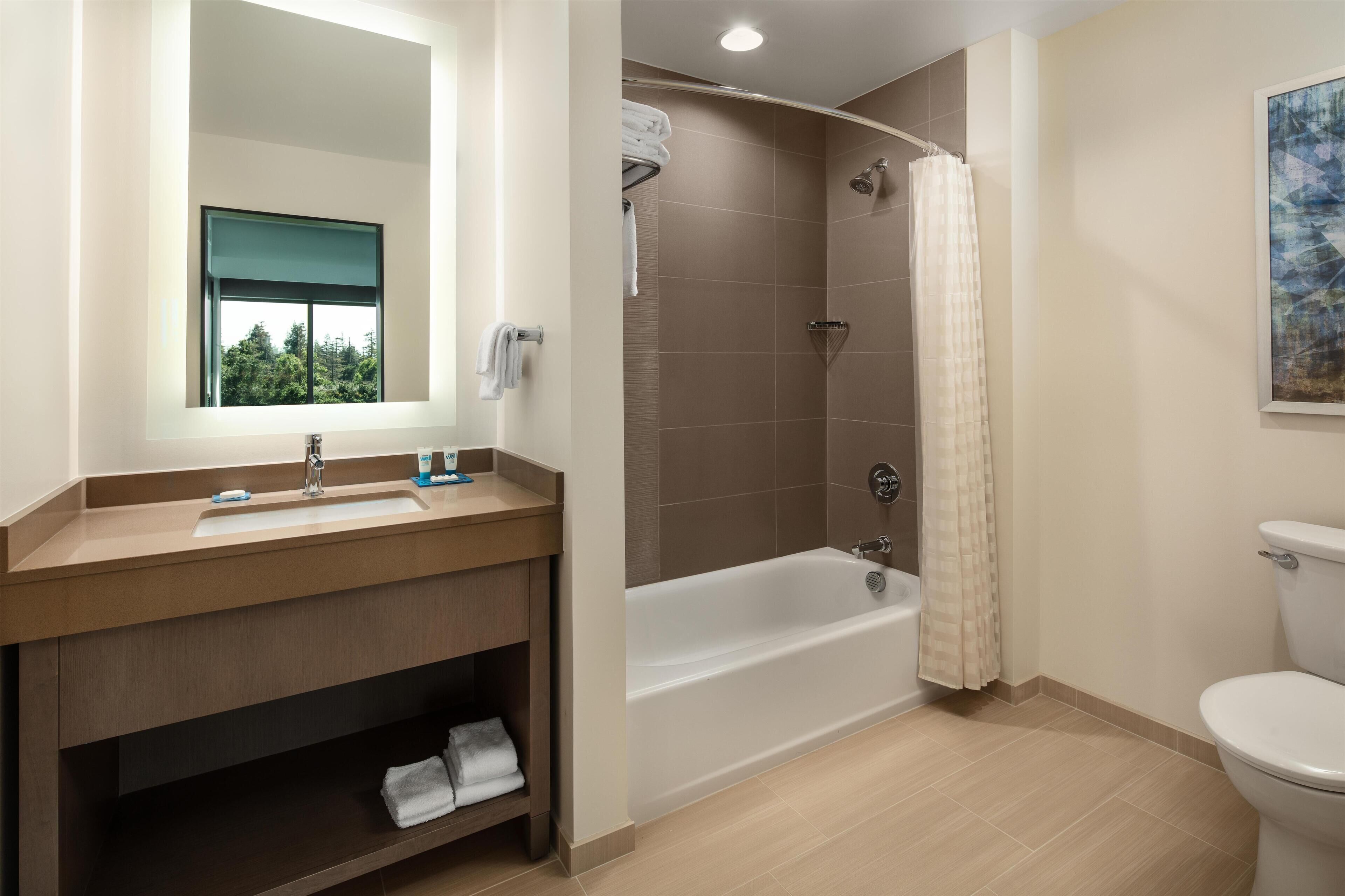 A bathroom with a sink, mirror, shower, and toilet.