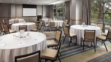 A conference room with round tables, chairs, and a projector screen.