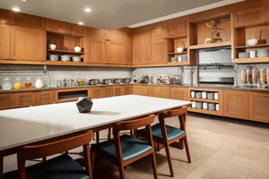 Una cocina moderna con armarios de madera, encimera blanca y una isla central con sillas.