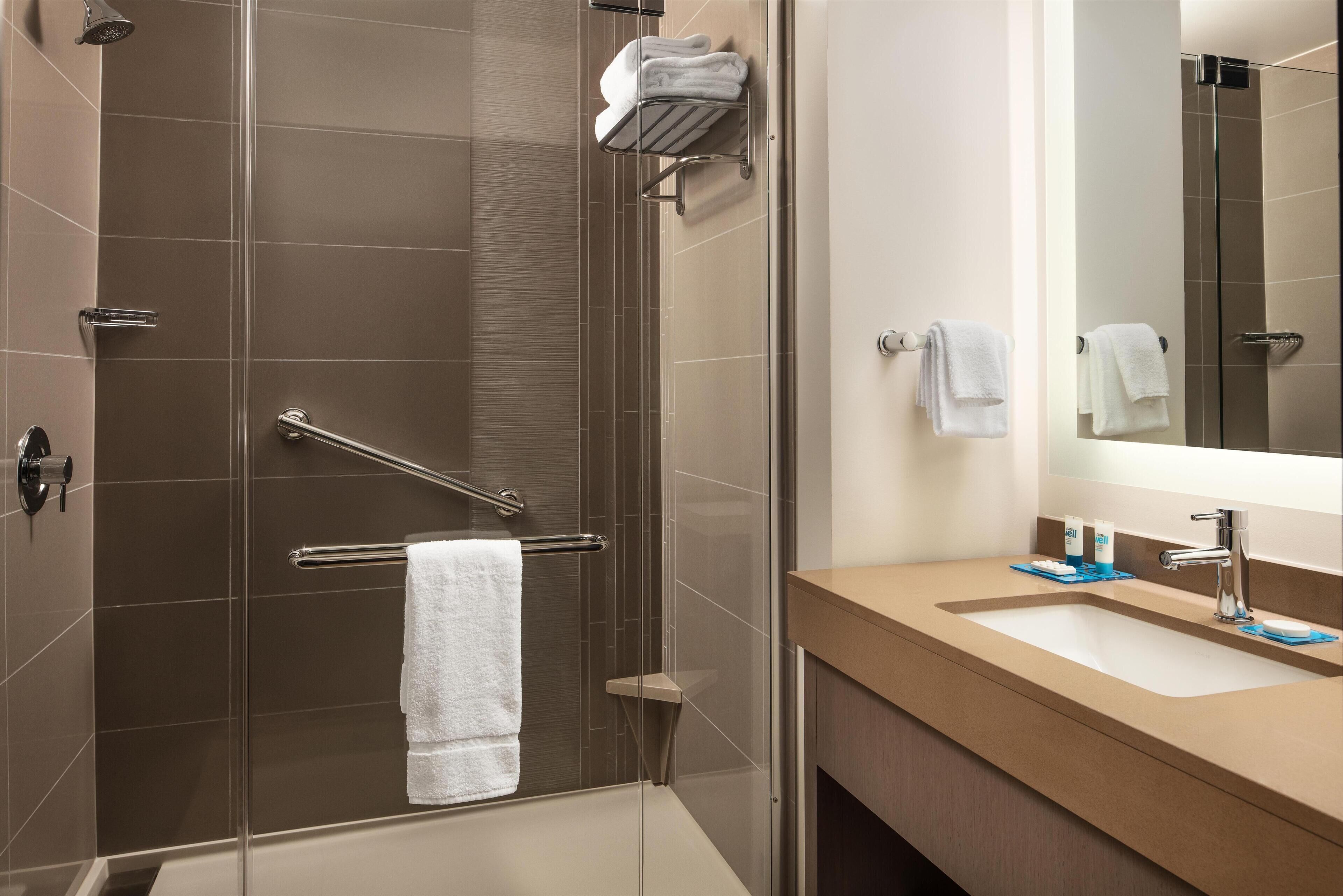 A modern bathroom with a glass shower enclosure, a towel rack, and a sink with a mirror.