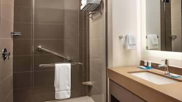 A modern bathroom with a glass shower enclosure, a towel rack, and a sink with a mirror.