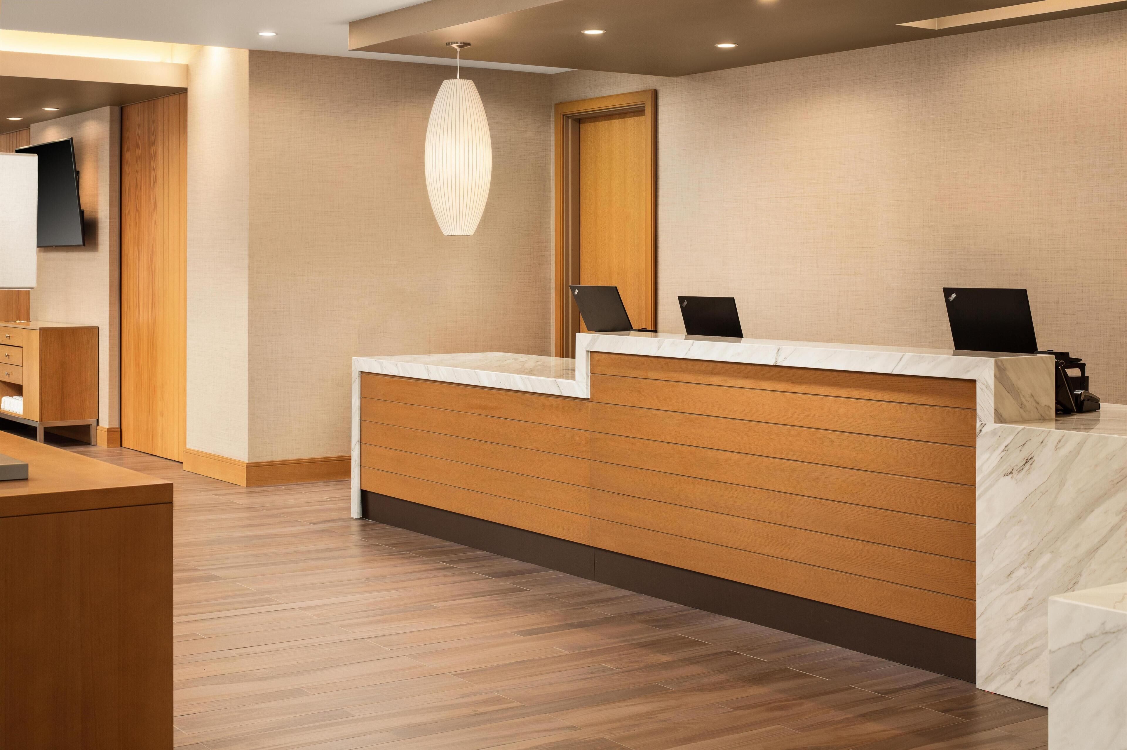 A reception desk with a wooden panel design, a marble counter, and a modern pendant light.
