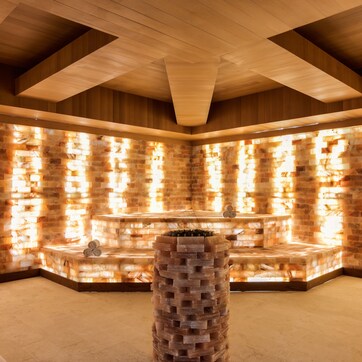 A spa area with a stone wall, wooden ceiling, and a central water feature.