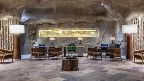 A modern interior with a central seating area, a stone wall, and a decorative light fixture.