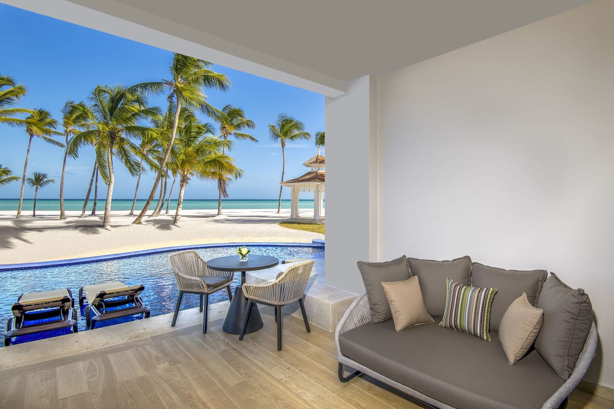 A room with a view of a beach, a pool, and a sofa.